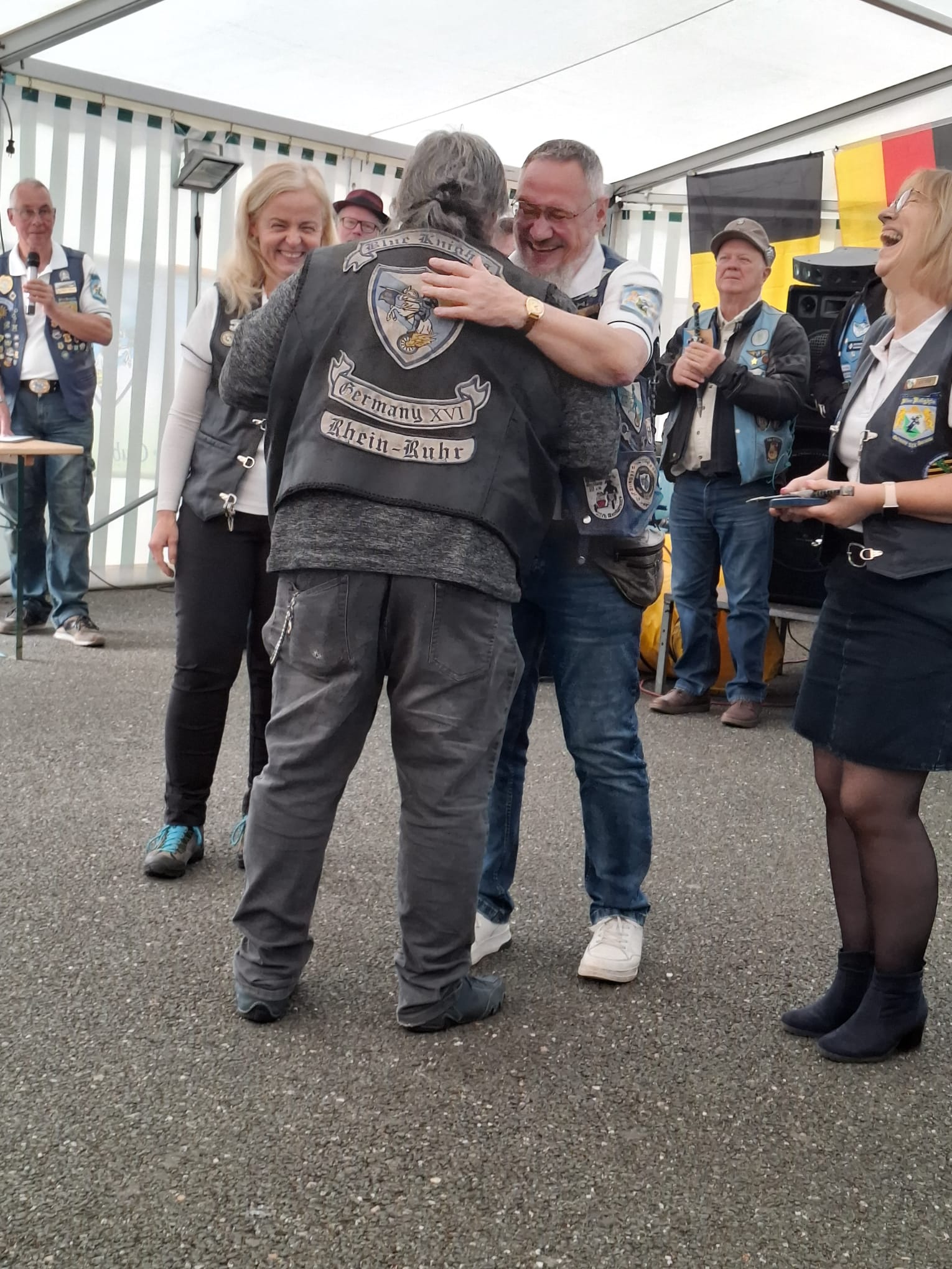 M&uuml;tze in der Kutte &bdquo;Germany XVI Rhein-Ruhr&ldquo; umarmt einen Gastgeber im Festzelt