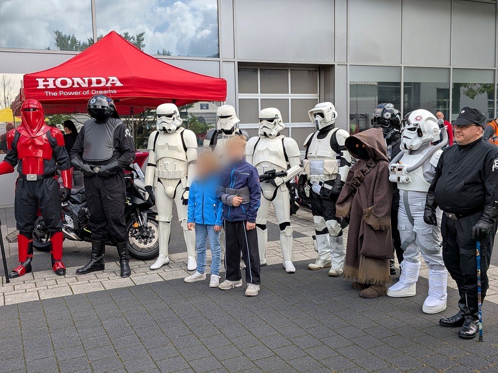 Star-Wars-Cosplayer mit Stormtroopern und imperialem Offizier vor dem Honda-Zelt; zwei mitposierende Kinder anonymisiert
